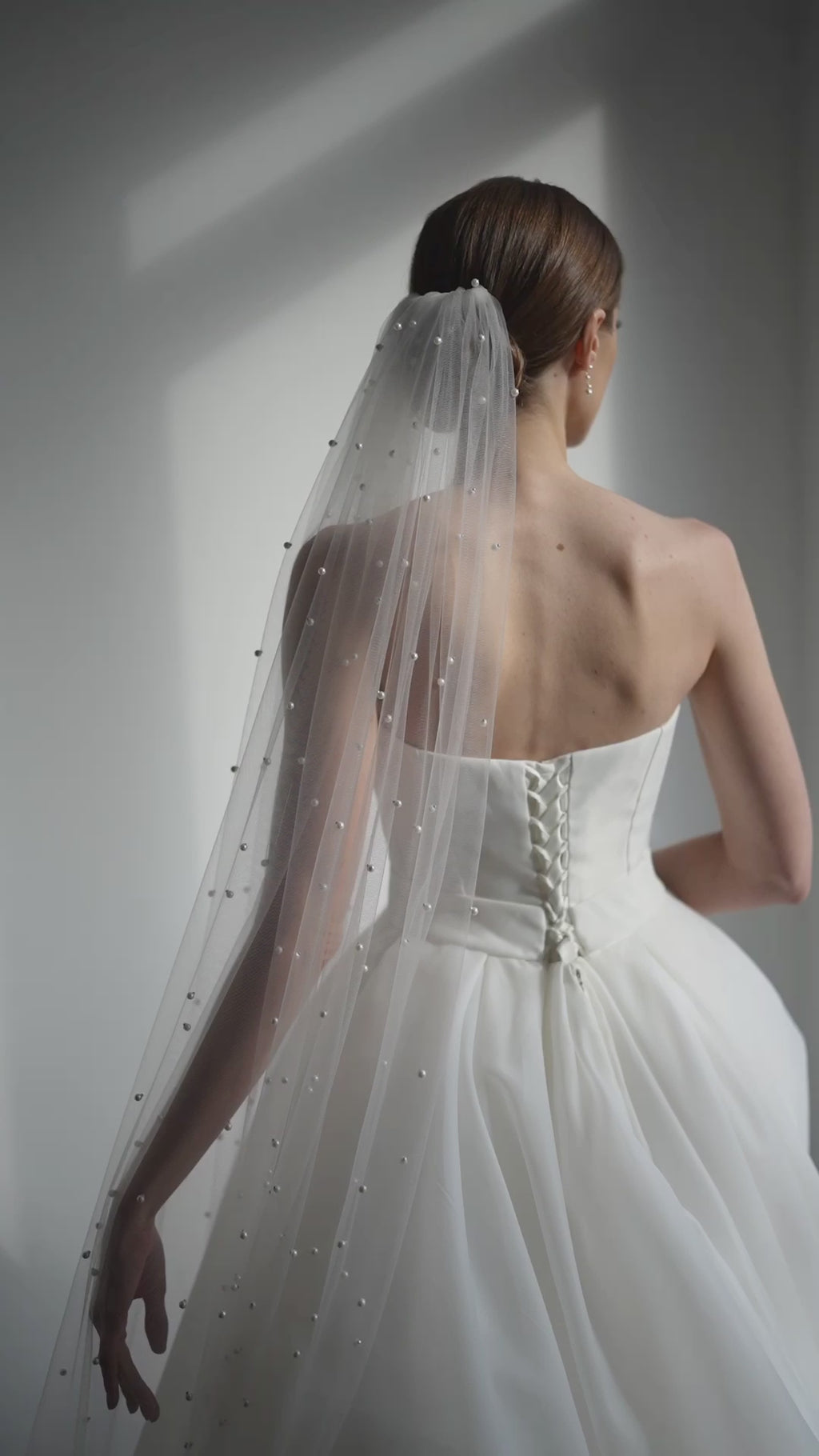 Bride wearing long cathedral veil with pearls on soft ivory tulle